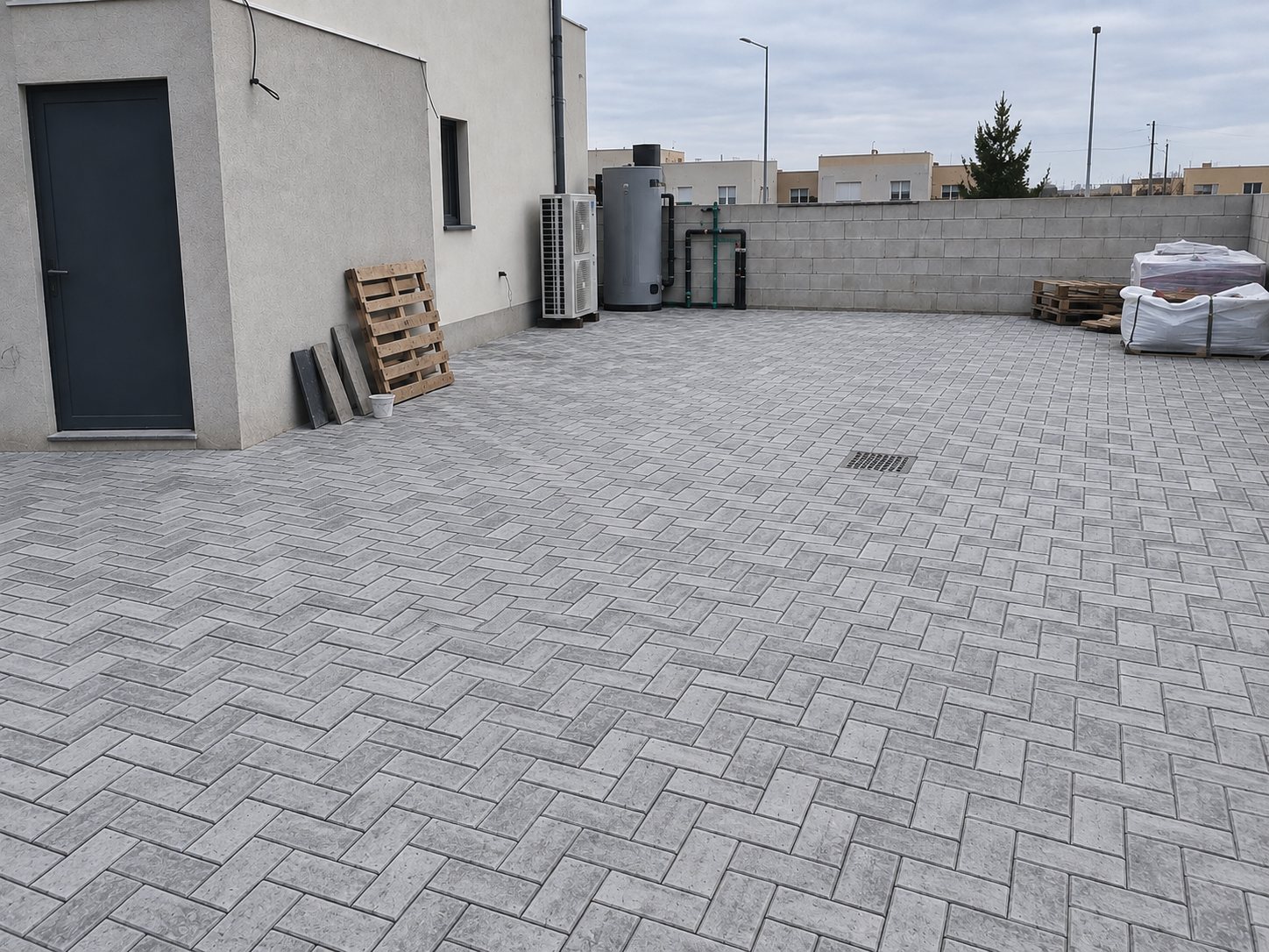Patio de servicio con hormigón impreso efecto adoquín gris por Hormiklass